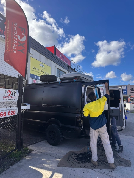 su505 Technician working on a black van outside the Super Auto Glass workshop